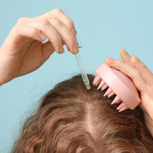 A woman is using a pink comb to style her hair